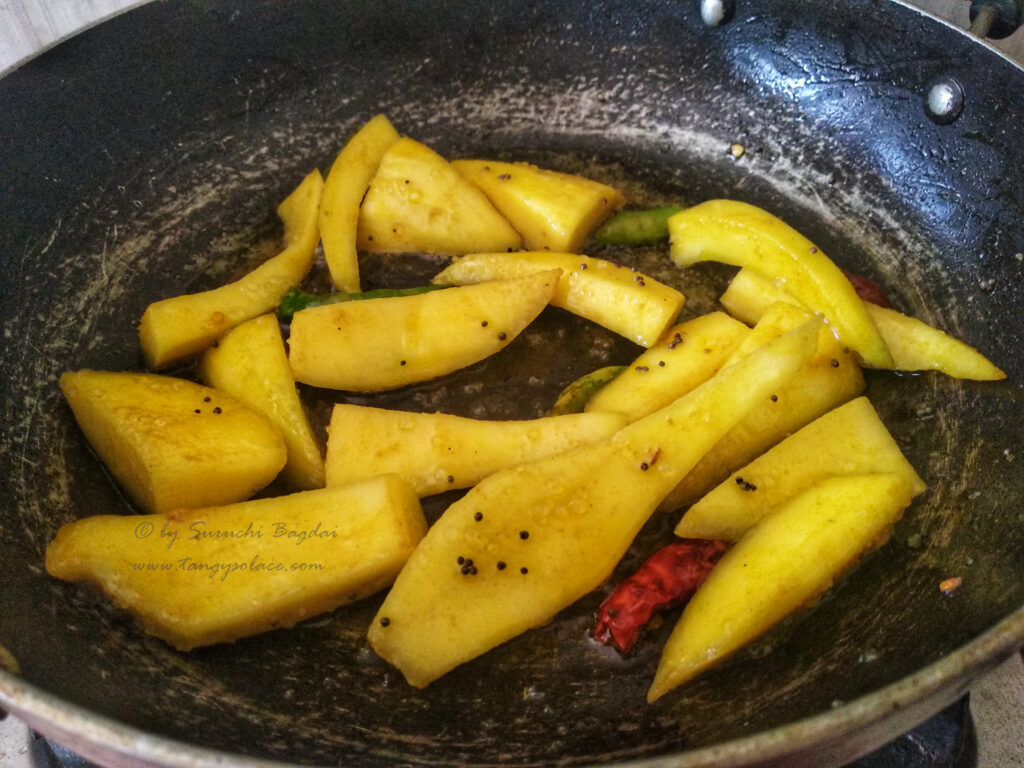 slices of raw mango cooking with panchphoran tempering