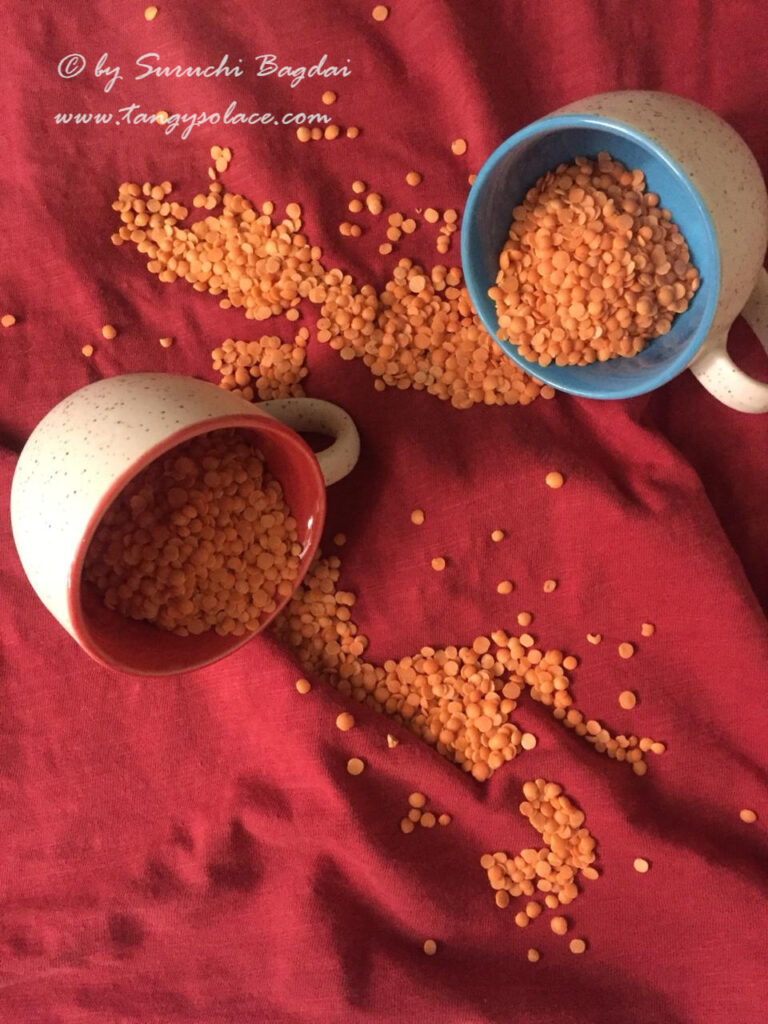 masoor dal flowing from cups on red background