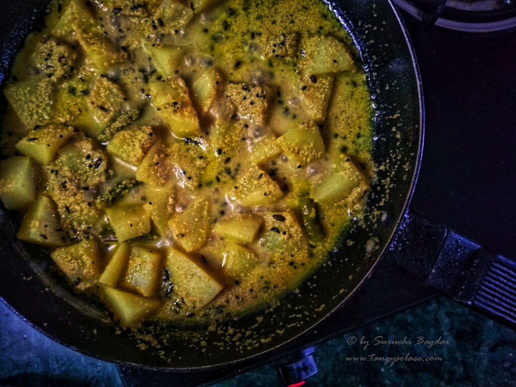 close up of aloo poshto simmering in nonstick pan