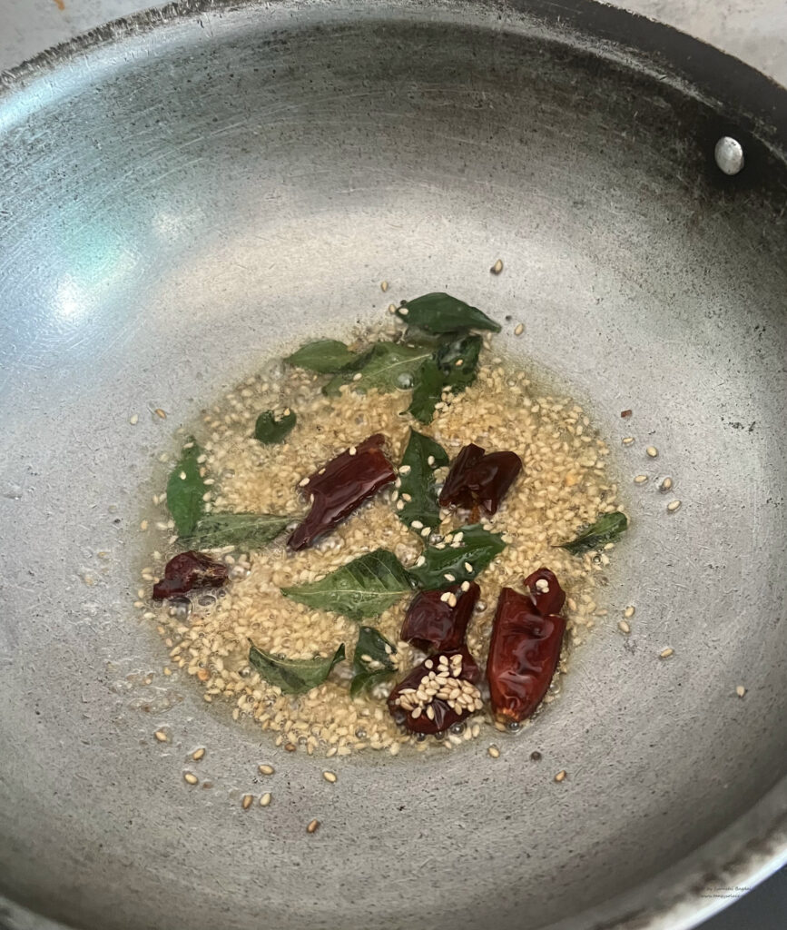 Tempering of mustard seeds, asafoetida, sesame seeds, curry leaves and broken red chillies in a saute pan